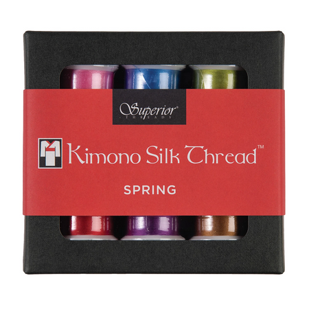 A box of Superior Company Kimono Silk Thread in the 'Spring' colorway, featuring six spools of thread in pink, blue, green, red, purple, and brown, wrapped in a red paper band.