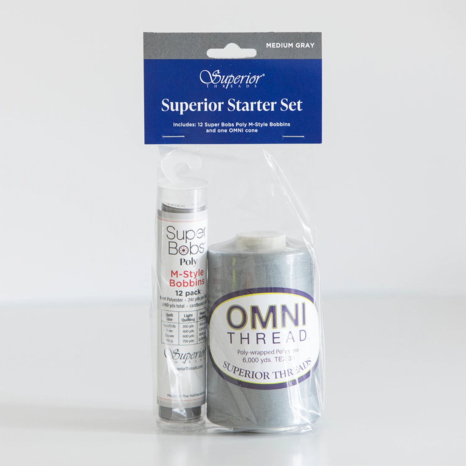 Superior Threads Superior Starter Set containing a 12-pack of Super Bobs Pully M-Type Bobbin thread and a spool of OMNI THREAD in medium gray, packaged in a clear plastic bag with a blue header card.