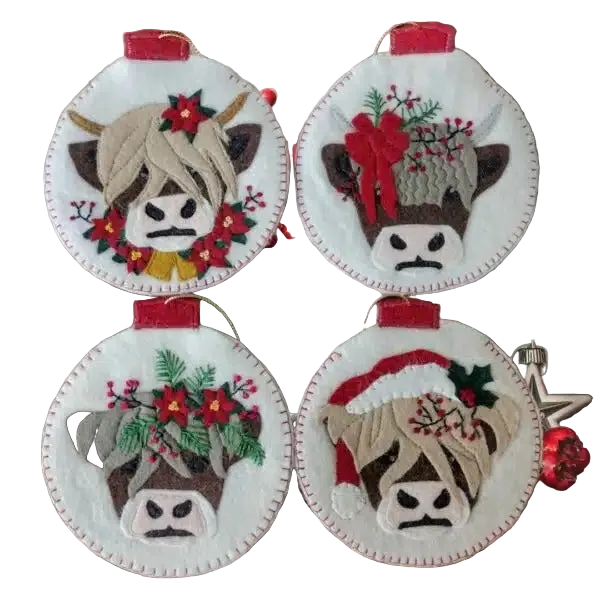 Four decorative cow ornaments with festive designs on a wooden surface.
