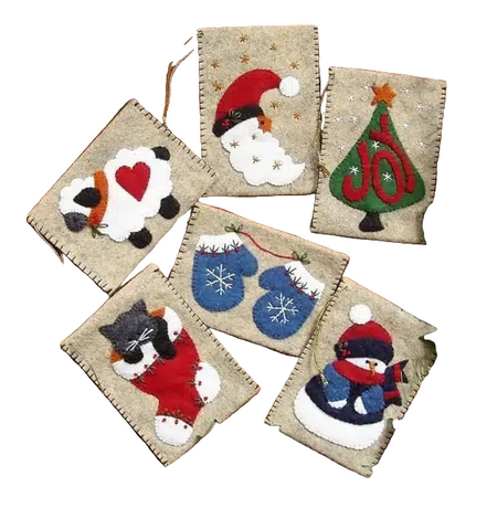 Set of felt Christmas ornaments on a wooden surface with greenery.