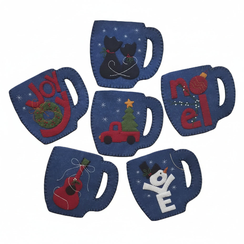 A collection of Christmas ornament kits shaped like mugs, with various festive designs, including 'Joy', 'Noel', and 'Love', in colors blue, red, green, gold, white, and black.